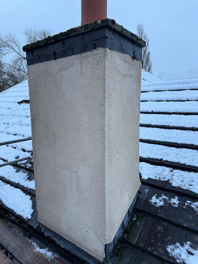 Freshly rendered chimney stack on a snowy roof
